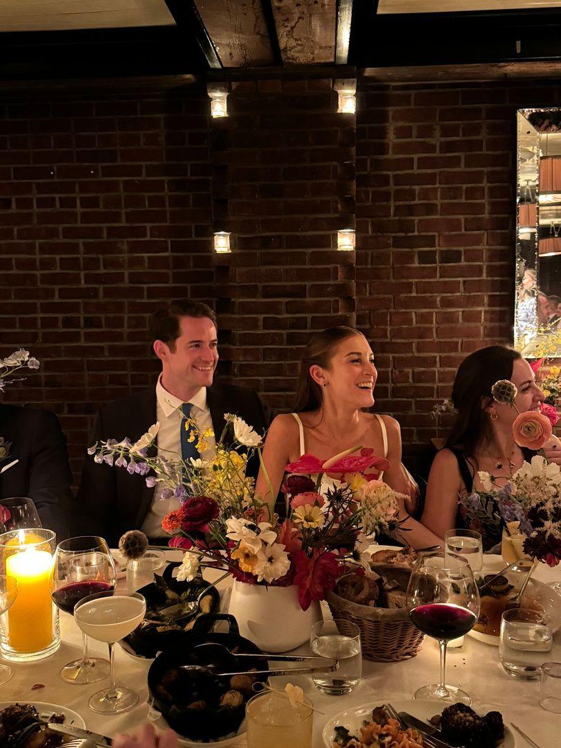 Bride and groom laughing while sitting at their table.