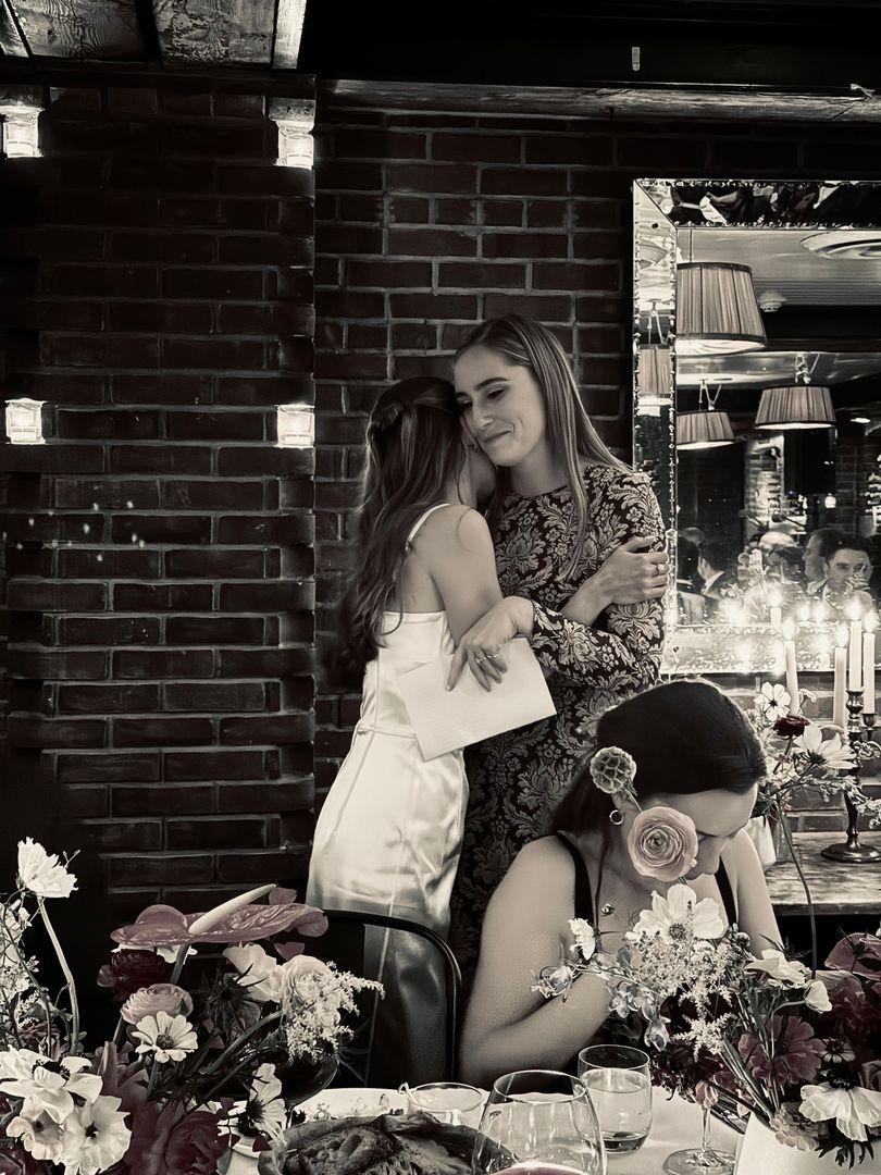 Bride hugging her friend, in black and white.