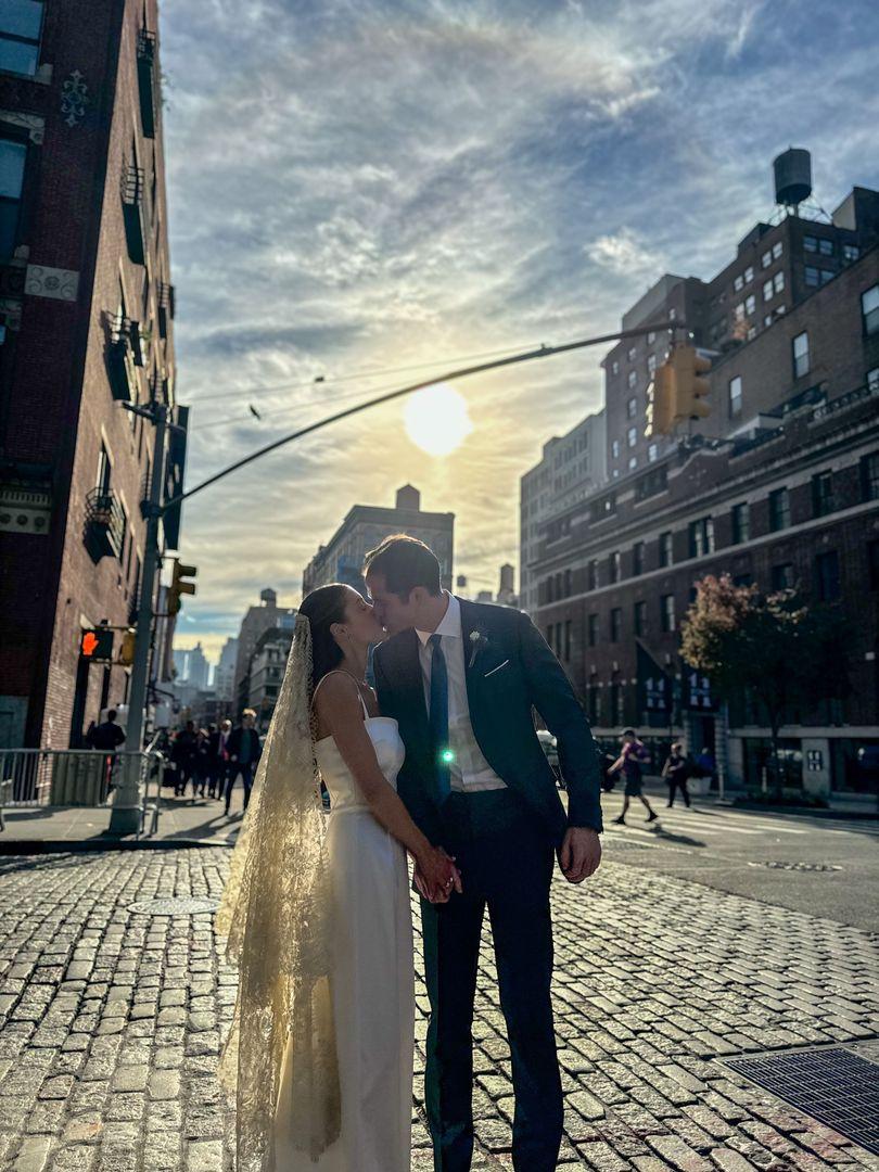 Bride and groom sharing a kiss in the street with the sun in the background.