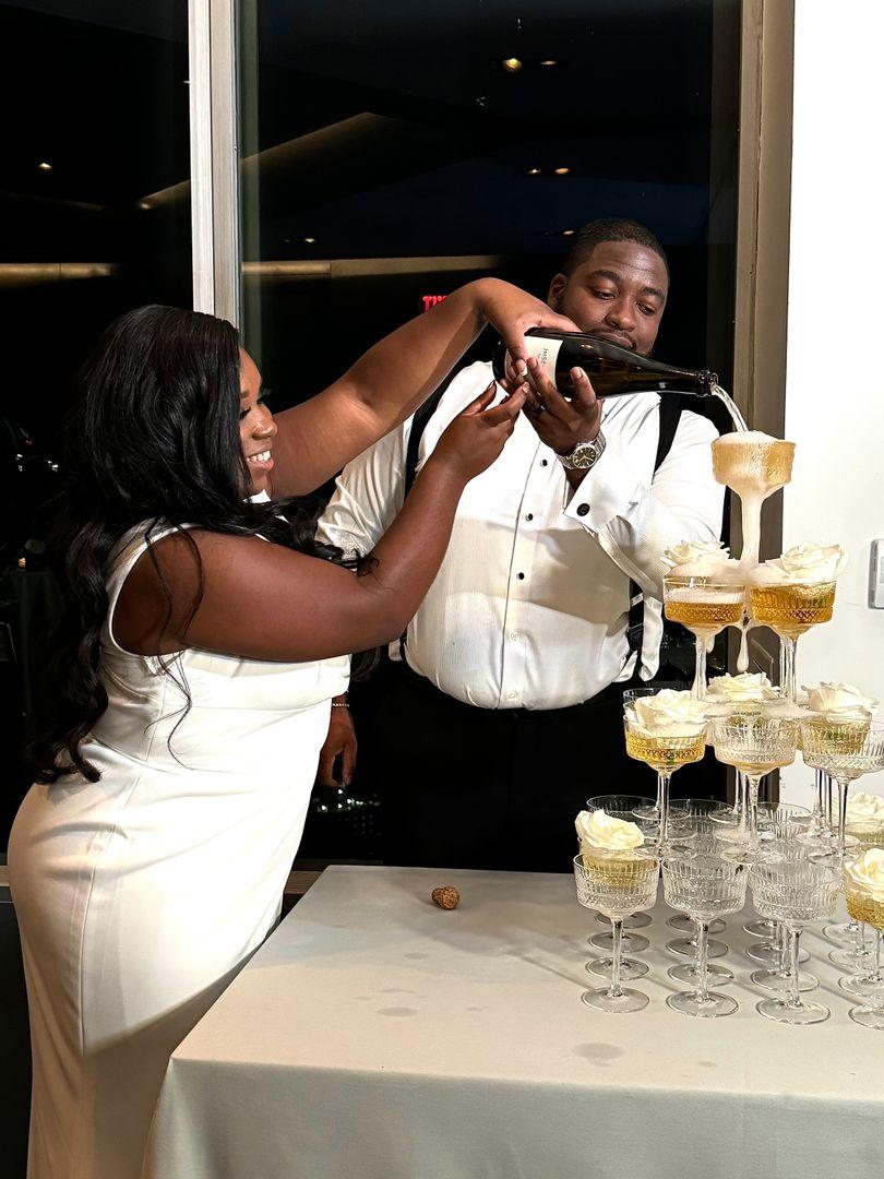 Bride and groom pouring champagne onto a champagne glass tower.