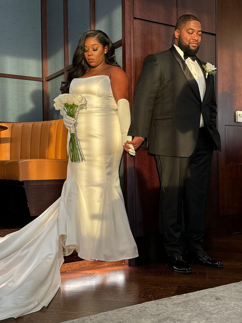 Bride and groom holding hands during prayer.