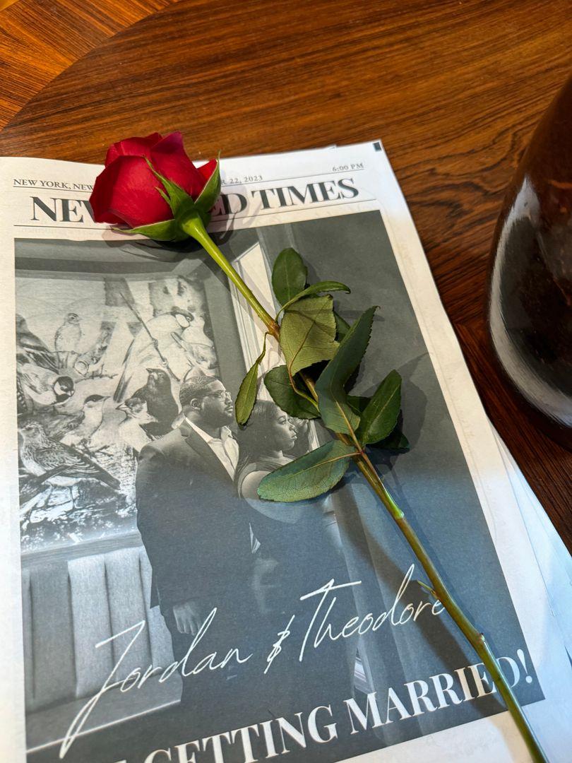 Bride and groom custom newspaper with a rose place on top.