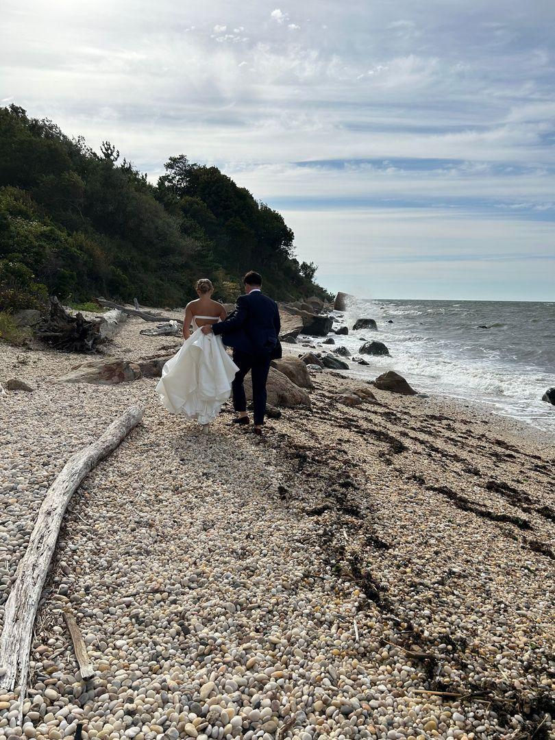 Bride and groom on beach walking away from the camera.