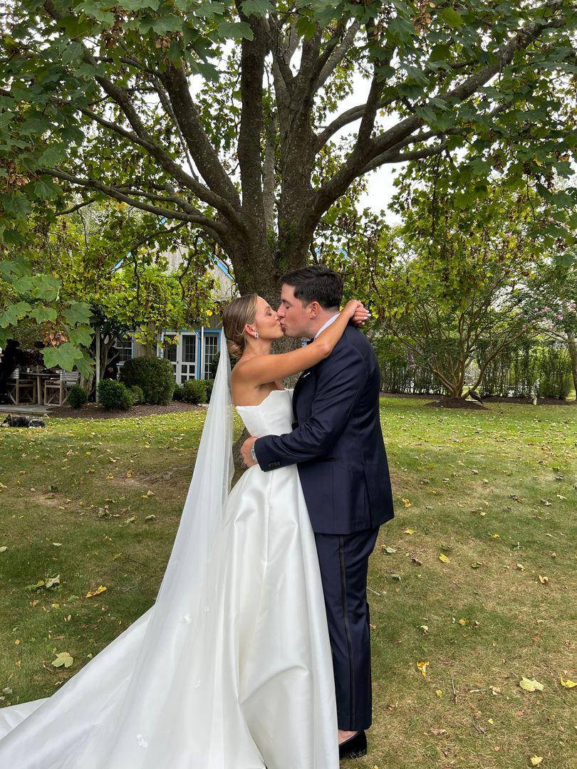 Bride and groom kissing in front of a tree.