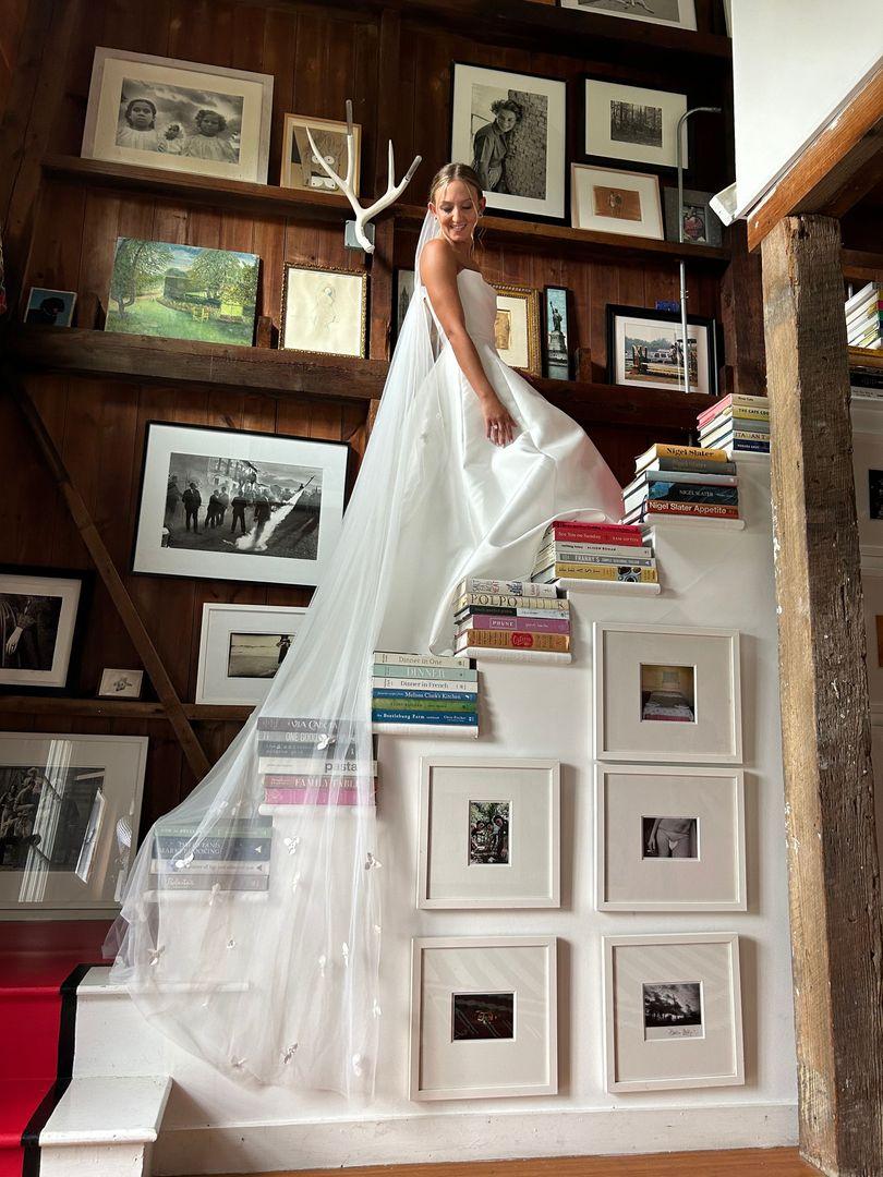 A bride standing on a staircase white the veil flowing behind her.