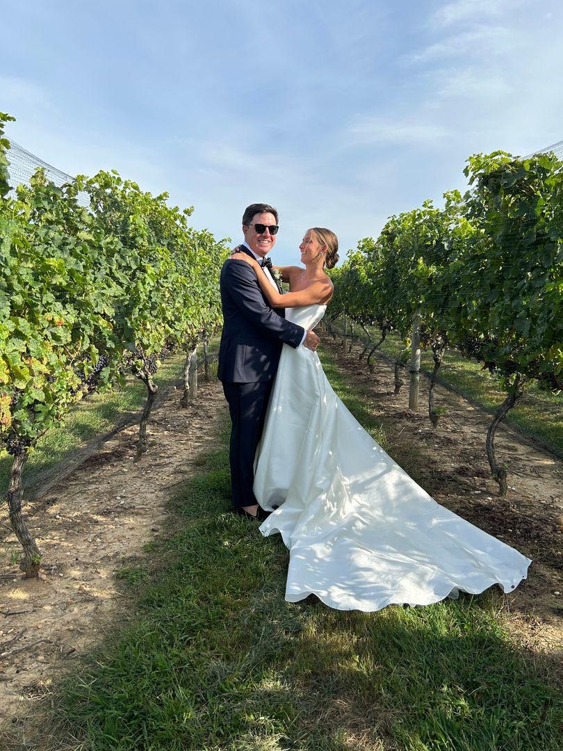 Bride an groom standing in a vineyard.